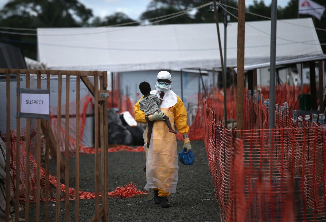 A Doctors Without Borders (MSF), health worker in protective clothing carries a child suspected of having Ebola at the MSF treatment center on October 5, 2014 in Paynesville, Liberia. The girl and her mother, both showing symptoms of the virus, survived and were released about a week later.