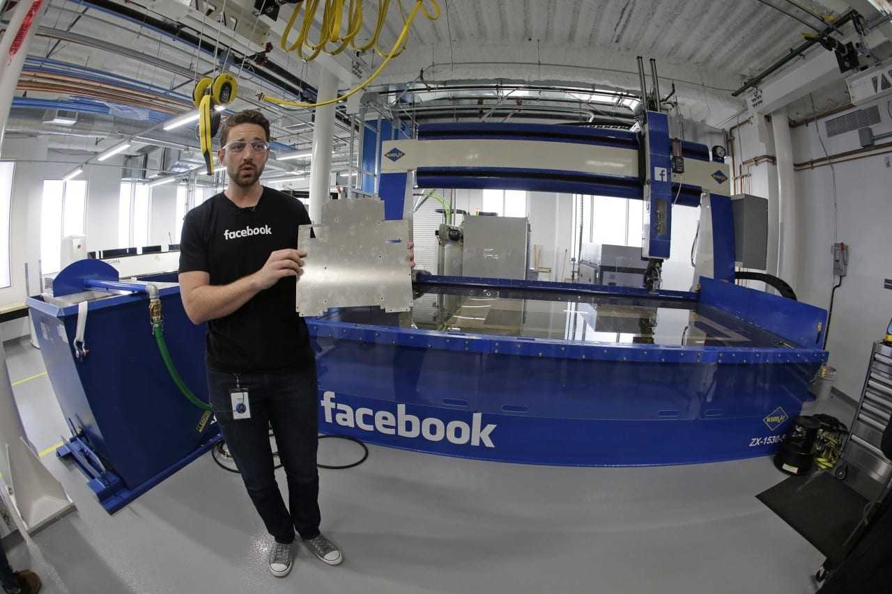 In this photo taken Tuesday, Aug. 2, 2016, model maker Spencer Burns, holds up a piece of sheet metal while standing in front of a water jet during a tour of Area 404, the hardware R&D lab, at Facebook headquarters in Menlo Park, Calif. (AP Photo/Eric Risberg) ORG XMIT: CAER502